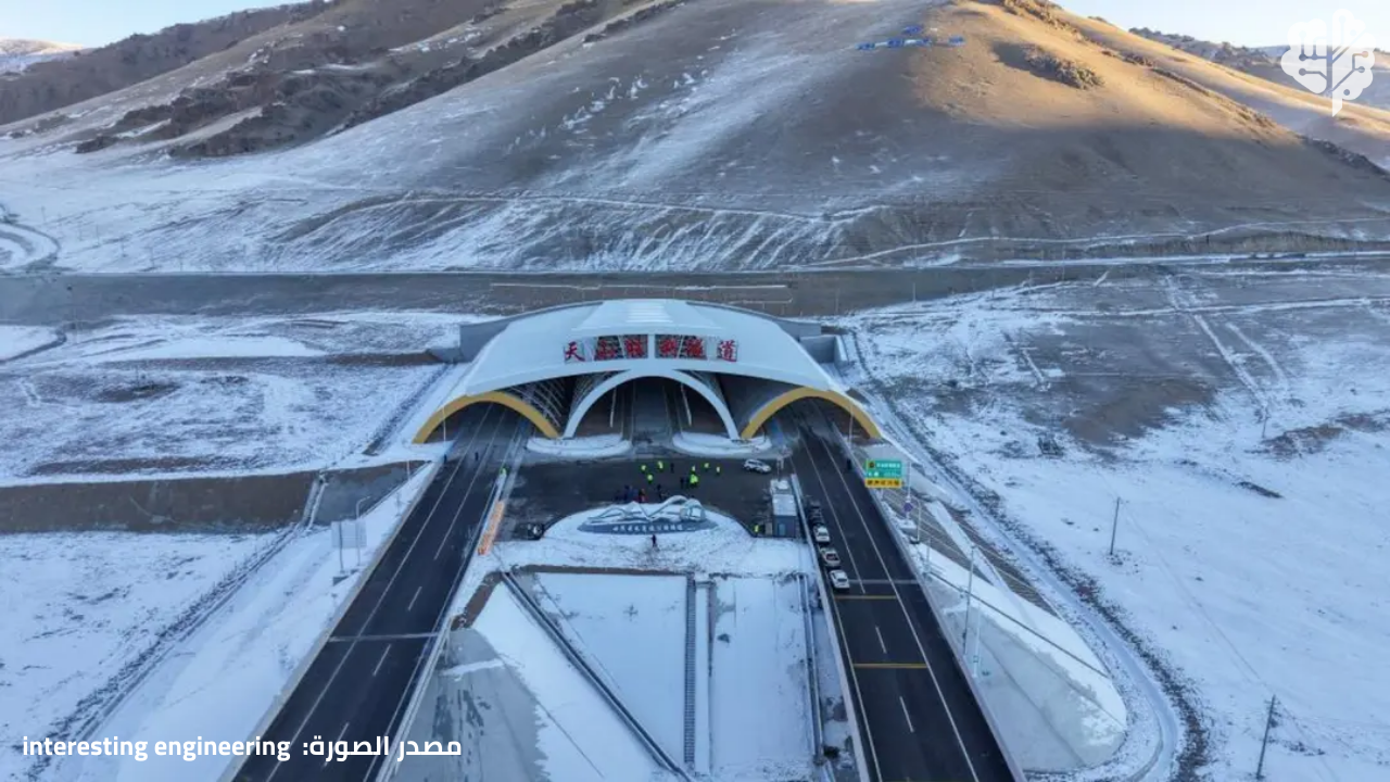 High-angle view of China’s Tianshan Shengli Tunnel, the world’s longest expressway tunnel at 22 km, showing highway lanes emerging from the mountain portal in Xinjiang’s Tianshan range at about 3,000 meters altitude and highlighting how it cuts Urumqi–Korla travel time to 3.5 hour